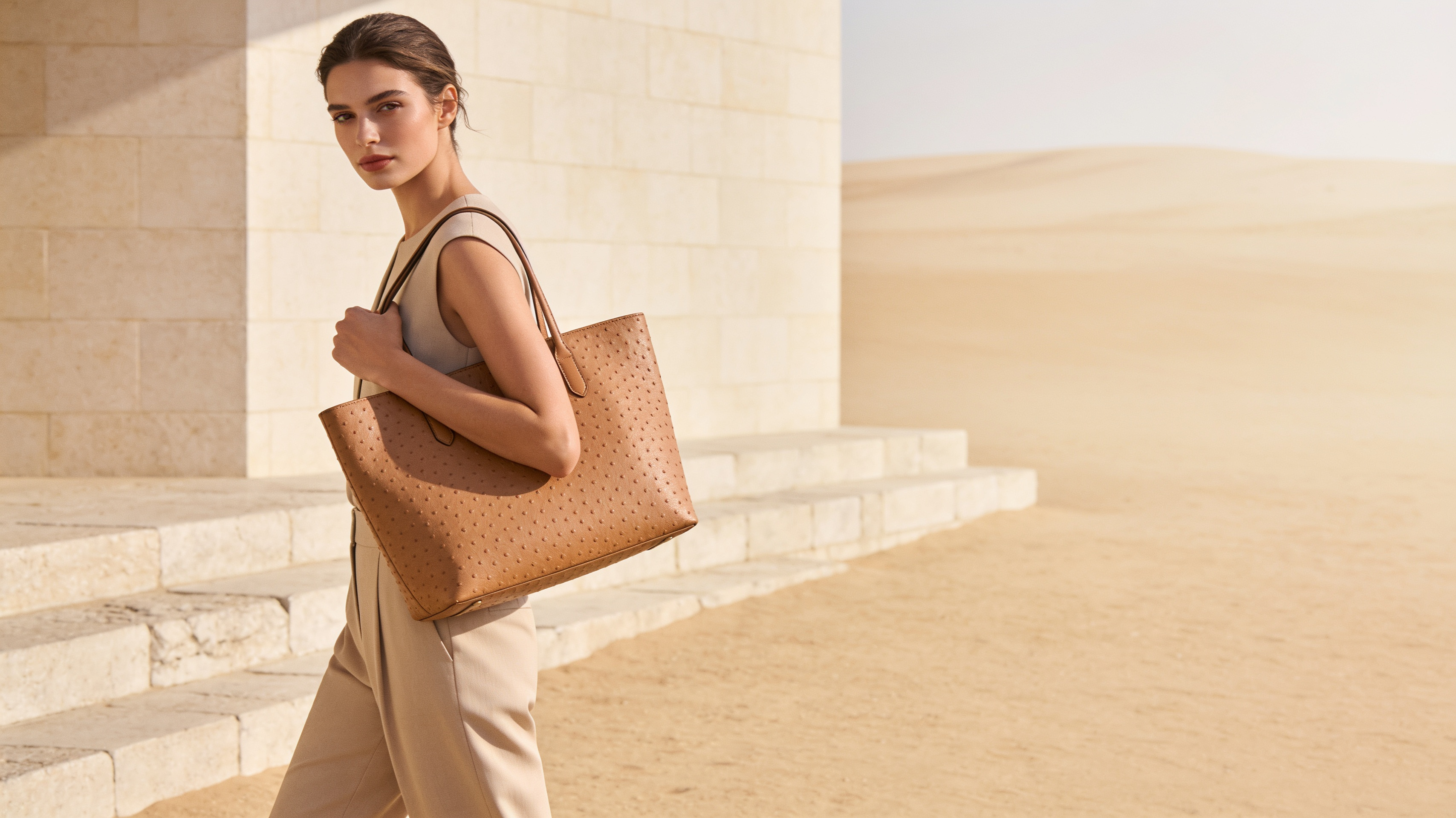 Woman carrying a tan Saint Loir leather tote in warm morning light