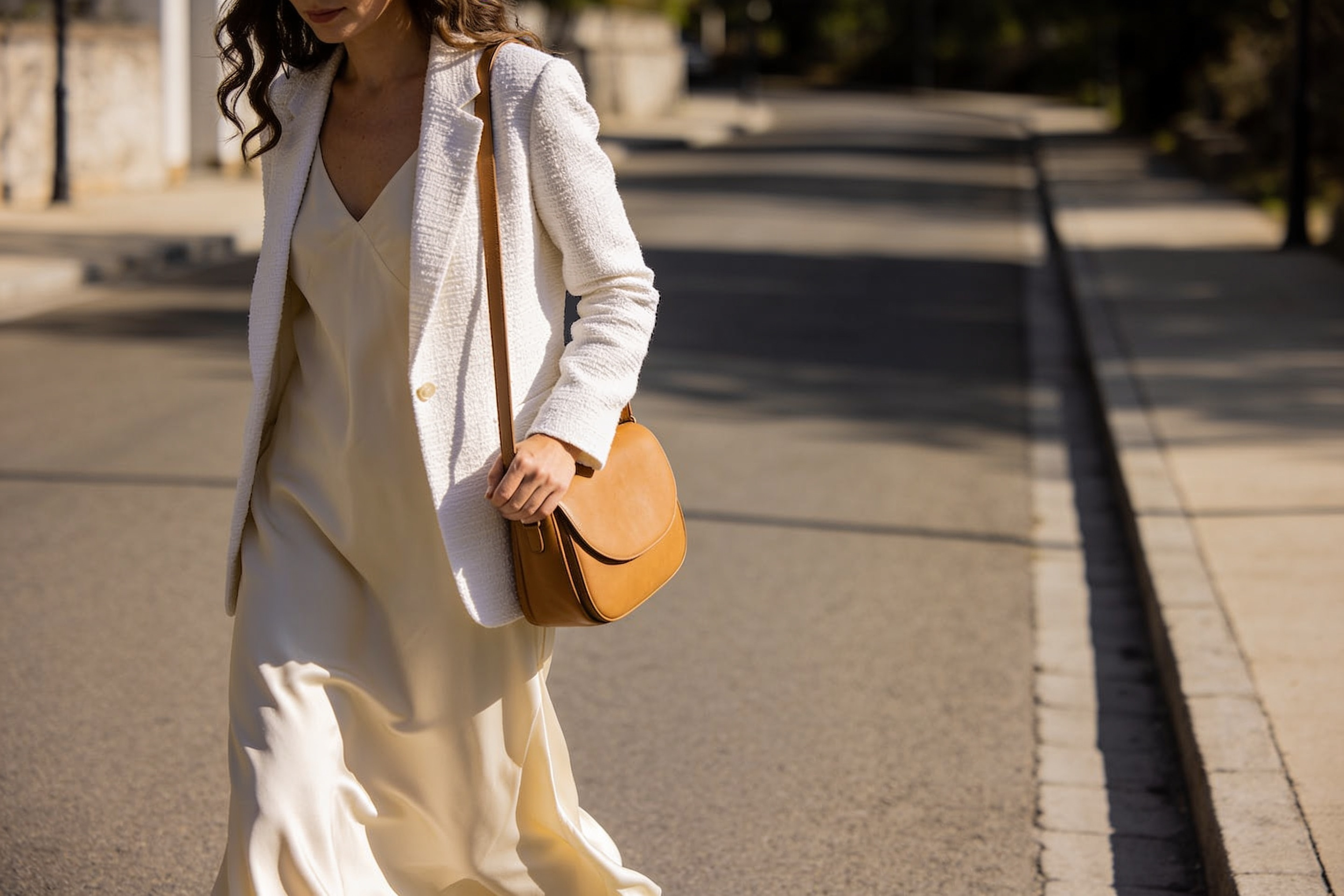 Woman carrying a tan Saint Loir shoulder bag on a sunlit street